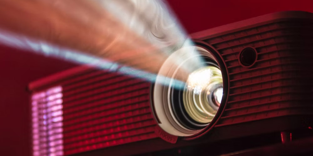 Apresentação artística em um espaço cultural, com uma performer no palco e um público diversificado assistindo.